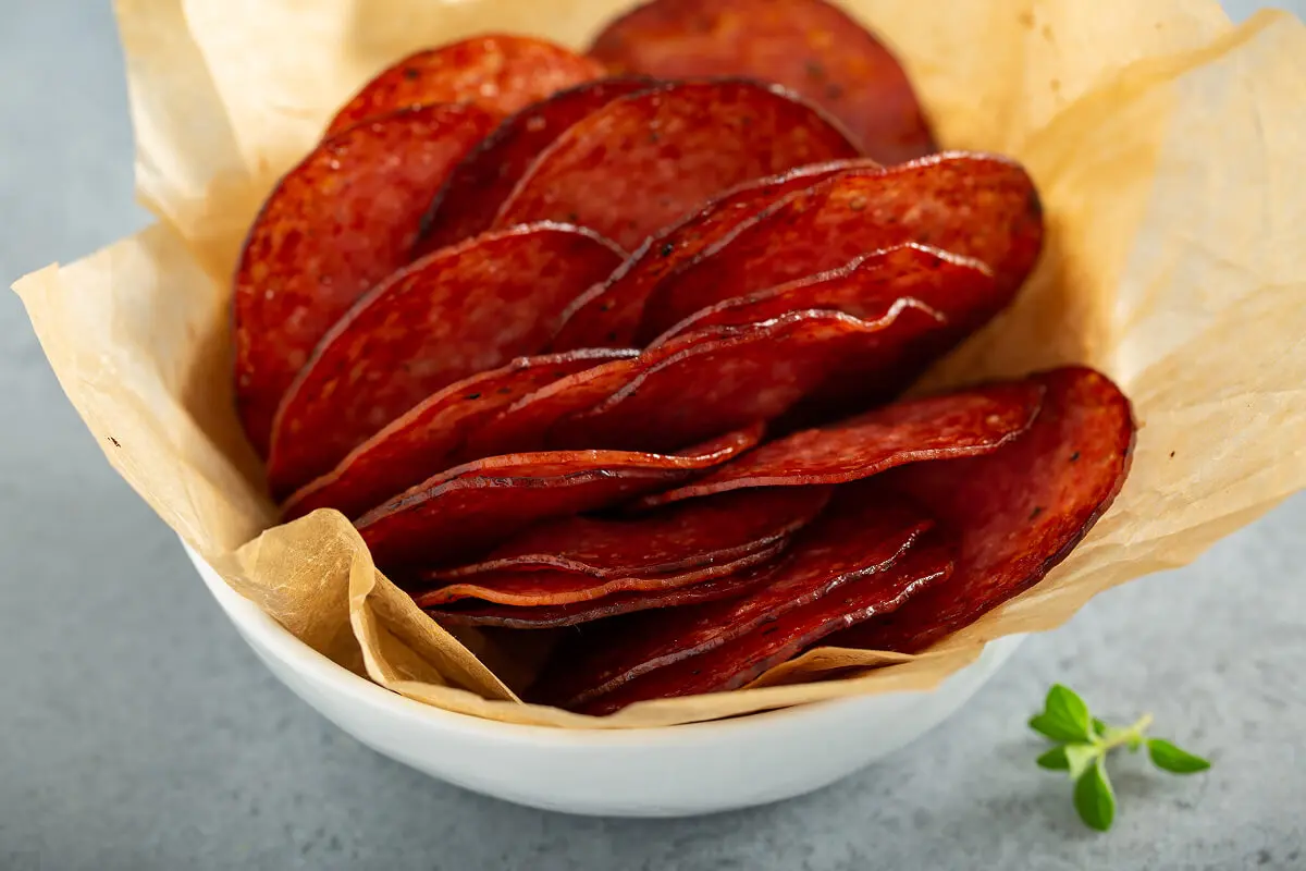 Crispy salami slices in paper-lined bowl.